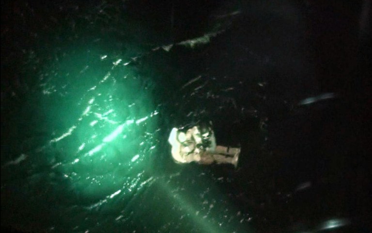 In this photo released by Yeosu Martime Poilice via Yonhap, a maritime policeman, wearing black helmet at top,  rescues a North Korean crew member of a sunken cargo ship in the sea,  off Yeosu, South Korea, Friday, April 4, 2014.  The Mongolian-flagged cargo ship, which was carrying 16 North Korean crew members, remains missing after it sent a distress signal early Friday in waters about 130 kilometers (80 miles) south of the southern port city of Yeosu, the coast guard said in a statement. Three people were rescued and identified themselves as part of a 16-member North Korean crew on the ship, the statement said. (AP Photo/ Yeosu Maritime Police via Yonhap) KOREA OUT