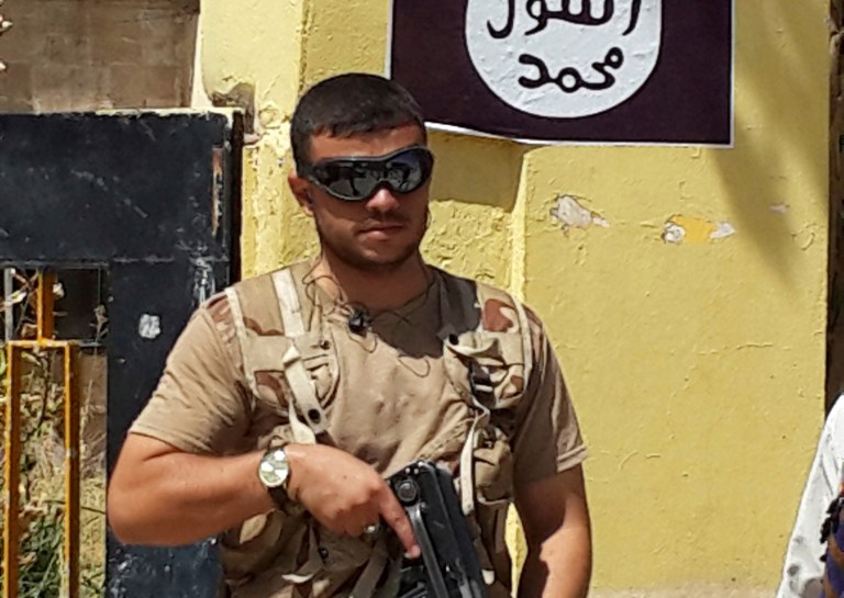 A fighter with ISIS stands guard in front of the headquarters of the Kurdistan Democratic Party on Aug. 7, 2014, in the Christian village of Bartella, northern Iraq. (AP Photo, File)
