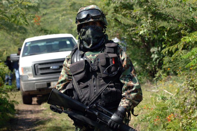 A Mexican navy marine guards the road that leads to the site where an alleged clandestine mass grave was found near the city of Iguala, Mexico, Saturday Oct. 4, 2014.  Mexican officials said a clandestine grave holding an undetermined number of bodies was found outside a town where violence last weekend resulted in six deaths and the disappearance of 43 students. (AP Photo/Alejandrino Gonzalez)
