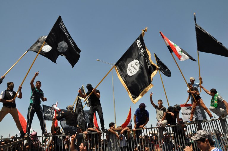 FILE - In this Friday, April 26, 2013 file photo, masked Sunni protesters wave Islamist flags while others chant slogans at an anti-government rally in Fallujah, 40 miles (65 kilometers) west of Baghdad, Iraq. Iraq's Sunni minority have felt maligned by the Shiite-led government in Baghdad, hounded by its security forces and increasingly threatened, once again, by the militias that terrorized them during the darkest days of sectarian bloodletting in 2006 and 2007. The community's anger has fueled the rampage of Islamic extremists across a third of the country, including Fallujah, and Sunnis say their demands must be met by the new Shiite-led government if it hopes to be more inclusive. (AP Photo/Bilal Fawzi, File)