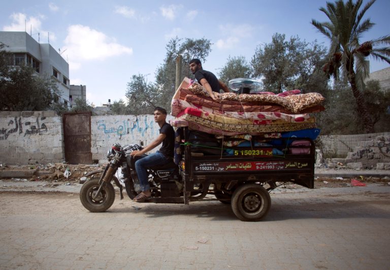 Palestinians with their belongings drive a motorbike back to their house in Gaza City's Shijaiyah neighborhood, Wednesday, Aug. 27, 2014. (AP Photo/Khalil Hamra)