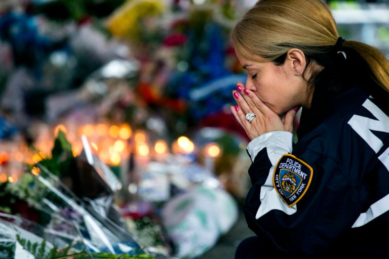 New York Police Department Lt. Tanisha Gurley visits a makeshift memorial, Tuesday, Dec. 23, 2014, near the site where NYPD officers Rafael Ramos and Wenjian Liu were murdered in the Brooklyn borough of New York. Police say Ismaaiyl Brinsley ambushed the two officers in their patrol car in broad daylight Saturday, fatally shooting them before killing himself inside a subway station. (AP Photo/Craig Ruttle)
