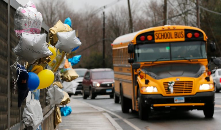 A school bus rolls towards a memorial for victims of the school shooting in Newtown, Conn., Tuesday, Dec. 18, 2012.  Newtown's school board has voted unanimously to delay any spending increase until more information is available about significant security costs. (AP Photo/Charles Krupa)