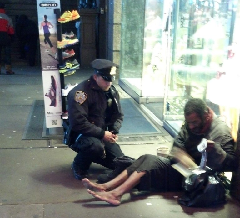   FILE- This file photo provided by Jennifer Foster from Nov. 14, 2012, shows New York City Police Officer Larry DePrimo presenting a barefoot homeless man in New York's Time Square with boots . (AP Photo/Jennifer Foster, File)  