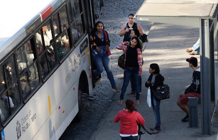 In this Tuesday, May 13, 2014 photo, passengers wait for transportation at a bus station, in Rio de Janeiro, Brazil. Muggings on public transportation, public beaches and in popular tourist areas are on the rise in Rio de Janeiro, eroding the strides the city had made in security in recent years as it geared up to host six World Cup matches and the 2016 Olympic. (AP Photo/Hassan Ammar)