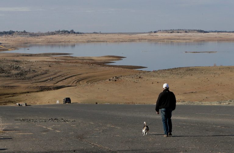 On Jan. 9, a visitor to Folsom Lake in California walks his dog down a boat ramp that is now several hundred yards away from the waters' edge. (AP Photo/Rich Pedroncelli, File)