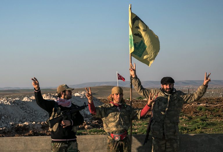 Syrian Kurdish militia members of YPG make a V-sign next to poster of Abdullah Ocalan, jailed Kurdish rebel leader, and a Turkish army tank in the background in Esme village in Aleppo province, Syria. In 2011, the Washington Post ignored State Department requests not to report on un-redacted cables onÂ U.S.-Turkey intel cooperation against Kurds. (AP Photo/Mursel Coban, Depo Photos, File)