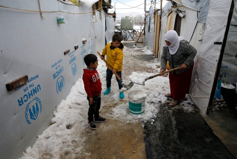 A Syrian woman with her kids remove the snow from the entrance of her tent, at an informal refugee camp in the eastern Lebanese town of Marj near the border with Syria, Lebanon, Saturday, Jan. 28, 2017. President Donald Trump has barred all refugees from entering the United States for four months, and indefinitely halted any from Syria, saying the ban is needed to keep out 