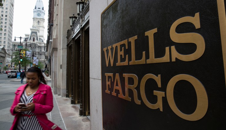 A woman walks past a Wells Fargo location in view of City Hall, left, in Philadelphia, Thursday, May 11, 2017. (AP Photo/Matt Rourke)