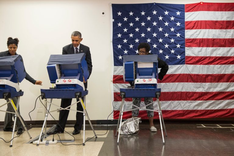 President Barack Obama, center, votes early in the midterm election at the Dr. Martin Luther King Community Service Center Monday, Oct. 20, 2014, in Chicago. Obama took a break from campaigning for Gov. Pat Quinn, D-Ill., to cast an early ballot for the election. (AP Photo/Evan Vucci)