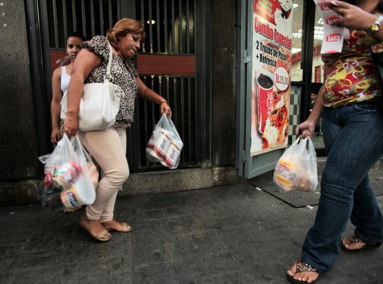 A customer leaves a private super market with her purchases, including toilet paper, in Caracas, Venezuela, Wednesday, May 15, 2013. First milk, butter, coffee and cornmeal ran short. Now Venezuela is running out of the most basic of necessities _ toilet paper. Blaming political opponents for the shortfall, as it does for other shortages, the embattled socialist government says it will import 50 million rolls to boost supplies. (AP Photo/Fernando Llano)
