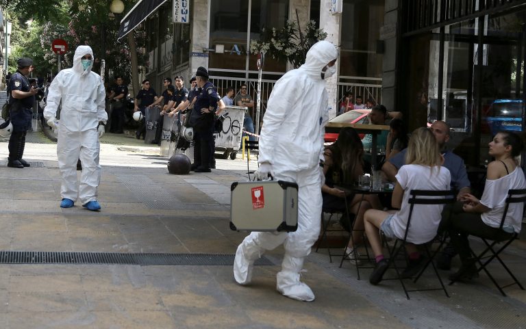Police bomb disposal experts, in white clothes, search for evidence, near the central Athens offices of the Pan-Hellenic Socialist Movement, or PASOK party, in central Athens, on Sunday, May 25, 2014 . Two shots from an AK-47 assault rifle were fired against the socialist PASOK party headquarters early Sunday. No one was at the premises at the time and there were no injuries. Greeks vote Sunday for  European Parliament and a second-round voting in local government polls. (AP Photo/Dimitris Messinis)