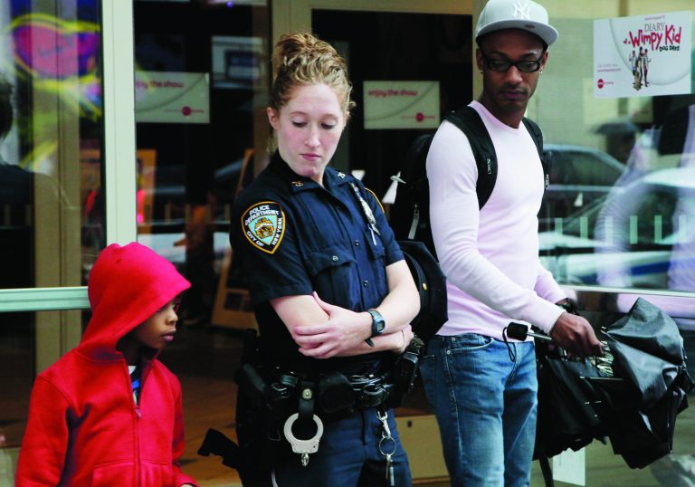 A New York City police officer watches as movie patrons arrive for a screening of 