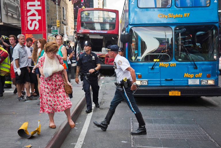 FILE- In this Aug. 5, 2014 file photo, woman, her arm bandaged and in a sling, leaves after being treated at the scene of a traffic accident apparently involving two double-decker tour buses in New York's Times Square. Although sightseeing buses are proliferating all over New York City, no single agency is charged with making sure their drivers and equipment are safe. (AP Photo/Bebeto Matthews, File)
