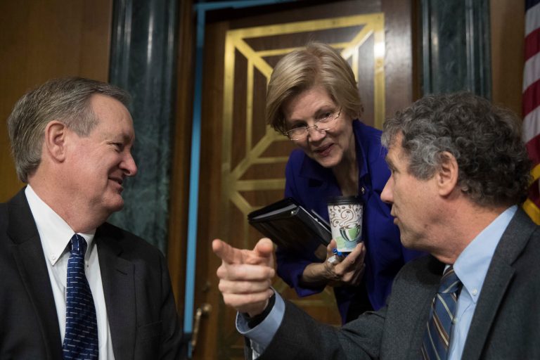 Senate Banking Committee member Sen. Elizabeth Warren, D-Mass., center, confers with Committee Chairman Sen. Mike Crapo, R-Idaho, left, and the committee's ranking member Sen. Sherrod Brown, D-Ohio, right. (AP Photo/Andrew Harnik)