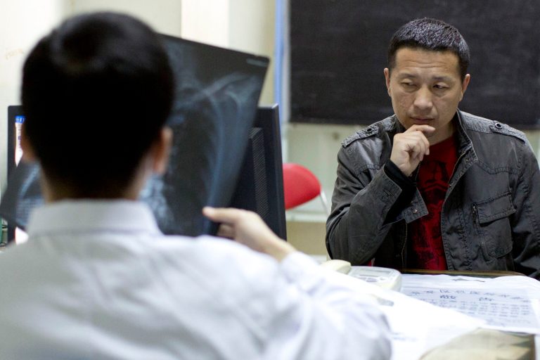 In this April 9, 2014 photo, lawyer Tang Jitian waits in an emergency room as a doctor checks his X-ray photo at a hospital in Beijing. Tang is among a group of four Chinese rights lawyers who allege they were tortured by police after being rounded up in late March outside a detention center in a farming community on the northeastern edge of China. (AP Photo/Alexander F. Yuan)