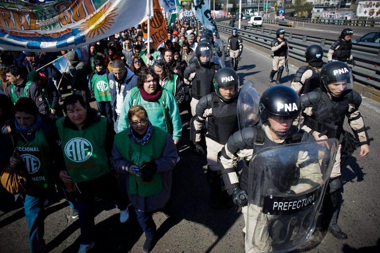 Riot police cordon off protesters partially blocking one of Buenos Aires' main access routes over the Riachuelo River in Argentina, Wednesday, Aug. 27, 2014.  CTA, a union umbrella group that opposes the government, started a 36-hour strike to demand more jobs, better salaries and tax cuts on salaries.  (AP Photo/Victor R. Caivano)