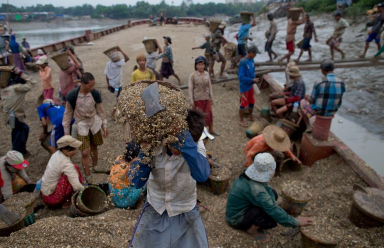 In this June 10, 2014 photo, a teenager lifts a basket of gravel, weighing about 19 kilograms (42 pounds) in a barge anchored in the banks of Yangon River, Myanmar. He receives 35 kyats ($0.037) for hauling a basket full of gravel from a boat to shore, walking a distance of about 30 meters (100 feet) on a narrow timber beam. Child labor remains widespread in Myanmar as the country tries to rebuild its economy after five decades of military misrule. More than one-third of Myanmar's children between the ages of 7 to 16 work, according to the United Nations. (AP Photo/Gemunu Amarasinghe)