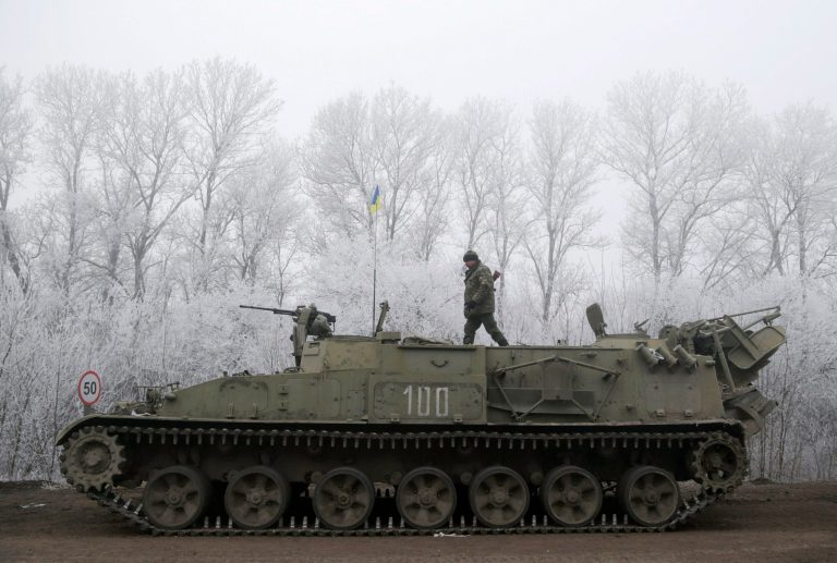 Ukrainian government soldier walks atop of his armored vehicle on the road between the towns of Dabeltseve and Artemivsk, Ukraine, Sunday, Feb. 15, 2015. International attention will be focused in the coming days on the strategic railway hub of Debaltseve, where Ukrainian government forces have for weeks been fending off severe onslaughts from pro-Russian separatists. A cease-fire was declared in eastern Ukraine, kindling slender hopes of a reprieve from a conflict that has claimed more than 5,300 lives. (AP Photo/Petr David Josek)