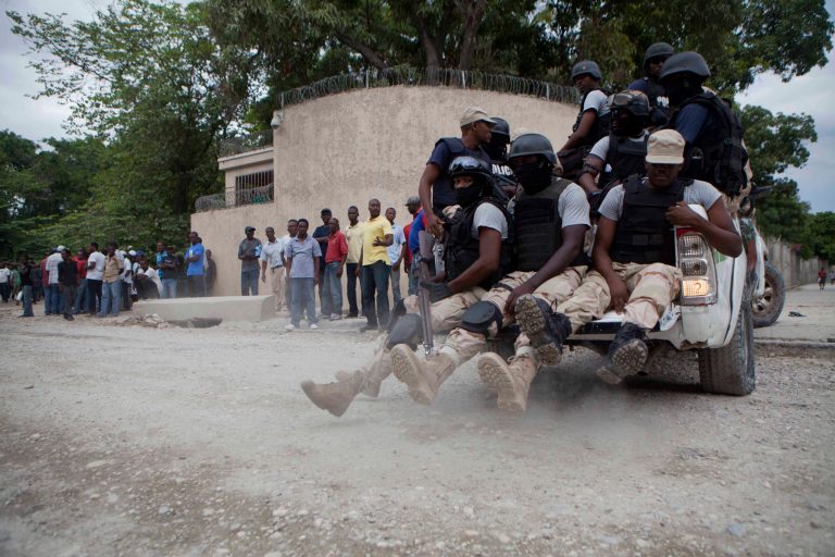 National police officers patrol outside the home of Haiti's former President Jean-Bertrand Aristide in Port-au-Prince, Haiti, Saturday, Sept. 27, 2014. Aristide supporters rallied outside his home Saturday after a new unit of police officers was abruptly posted outside the walled compound in the capital amid fears that the ex-leader faces arrest for failing to heed a court summons. (AP Photo/Dieu Nalio Chery)