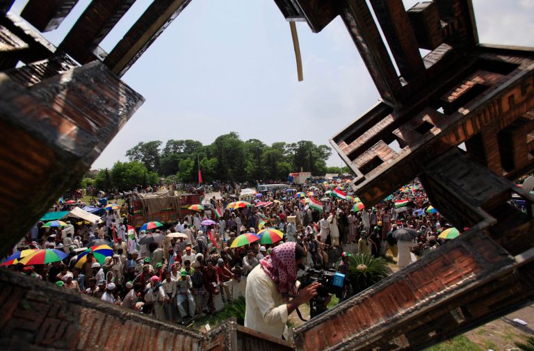 Supporters of anti-government cleric Tahir-ul-Qadri block an entrance of the parliament, seen in background, during a protest at Islamabad's high-security Red Zone in Islamabad, Pakistan, Wednesday, Aug. 20, 2014. Jubilant anti-government demonstrators in Pakistan are claiming victory after tearing down barricades and occupying a key road outside Parliament, where they are demanding the resignation of Prime Minister Nawaz Sharif.  (AP Photo/Anjum Naveed)