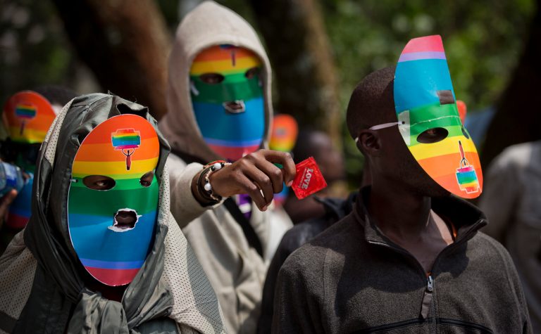 FILE - In this Monday, Feb. 10, 2014 file photo, Kenyan gays and lesbians and others supporting their cause wear masks to preserve their anonymity and one holds out a condom, as they stage a rare protest, against Uganda's increasingly tough stance against homosexuality and in solidarity with their counterparts there, outside the Uganda High Commission in Nairobi, Kenya. Ugandan President Yoweri Museveni met in his office with a team of U.S.-based rights activists concerned about legislation that would impose life sentences for some homosexual acts and made clear he had no plans to sign the bill, according to Santiago Canton of the Robert F. Kennedy Center for Justice and Human Rights who attended the Jan. 18, 2014 meeting, but one month later Museveni appears to have changed his mind, saying through a spokesman in February 2014 that he would sign the bill 