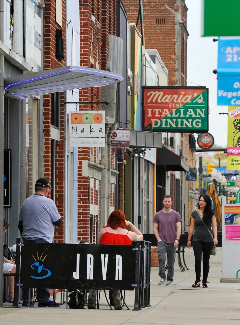 From left, Jordan Miller and Laura Crawford walk down Nine Mile in downtown Ferndale, Mich., on May 9, 2014.  Participants in the National Main Streets Conference plan to gather in Detroit starting this weekend to boost nationwide efforts to rebuild vibrant, economically viable downtowns. The 2014 National Main Streets Conference starts Sunday in downtown and runs through May 21. About 1,200 people are expected to attend the event, to share optimism for the future of downtowns,  (AP Photo/Detroit News, Daniel Mears)  DETROIT FREE PRESS OUT; HUFFINGTON POST OUT