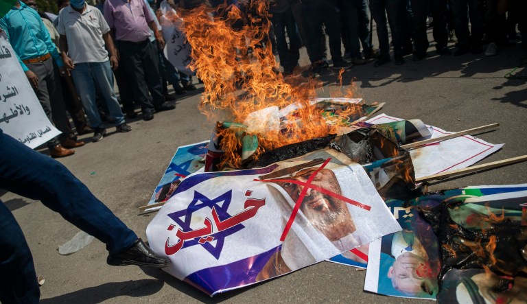 Palestinians burn pictures of U.S. President Donald Trump, Israeli Prime Minister Benjamin Netanyahu, Bahrain's King Hamad bin Isa Al Khalifa and and Abu Dhabi Crown Prince Mohammed bin Zayed al-Nahyan, during a protest against the United Arab Emirates and Bahraini normalization agreement with Israel, in Gaza City, Tuesday, Sept. 15, 2020. Israel is set to sign agreements with the UAE and Bahrain at the White House on Tuesday. Arabic on poster with representation of an Israeli flag reads, "traitor."
