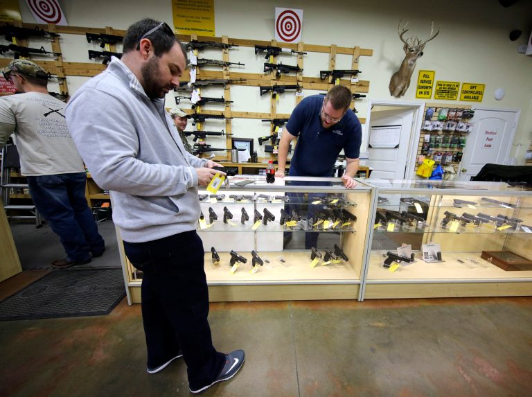 David Foley, center, looks as a handgun while shopping at the Spring Guns and Ammo store in Spring, Texas. (AP Photo/David J. Phillip)