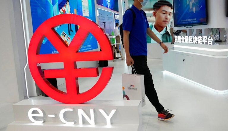 A visitor passes by a logo for the e-CNY, a digital version of the Chinese Yuan, displayed during a trade fair in Beijing, China, Sunday, Sept. 5, 2021. China's central bank on Friday, Sept. 24, 2021 declared all transactions involving Bitcoin and other virtual currencies illegal, stepping up a campaign to block use of unofficial digital money. It is developing an electronic version of the country's yuan for cashless transactions that can be tracked and controlled by Beijing.