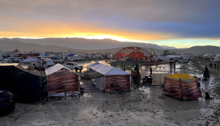 This photo shows tents between puddles and mud on the grounds of the 