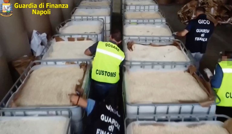 This image taken from a video shows customs police officers inspecting boxes full of amphetamines pills that were seized at the Salerno harbor, southern Italy, Wednesday, July 1, 2020. Italian police have seized 14 tons of amphetamines, allegedly produced in Syria by Islamic State group to fund terrorist activities and destined for the European illegal drug market.