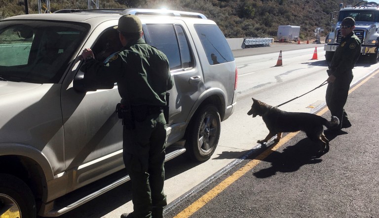 In this Thursday, Dec. 14, 2017 photo, border patrol agents use a drug sniffing dog to check vehicles at California's Pine Valley checkpoint, on the main route from Arizona to San Diego.