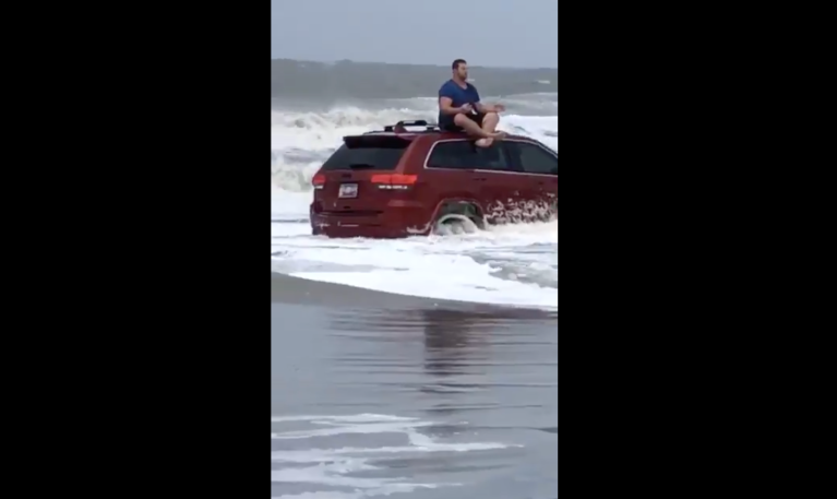 Man meditates on top of Jeep that was swept away during Hurricane Dorian.