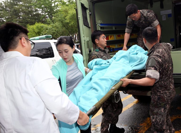 A wounded South Korean soldier who killed five comrades in a shooting incident on a stretcher is carried from an ambulance upon arrival at a hospital in Gangneung, South Korea, Monday, June 23, 2014. The South Korean army captured the soldier Monday who it says killed five comrades and then fled into the forest where he holed up with a rifle for two days before shooting himself as pursuers closed in. The massive manhunt ended when the 22-year-old sergeant, surnamed Yim, shot himself in the upper left chest as his father and brother approached, pleading with him to surrender, a Defense Ministry official said. (AP Photo/Yonhap, Lee Sang-hack)  KOREA OUT