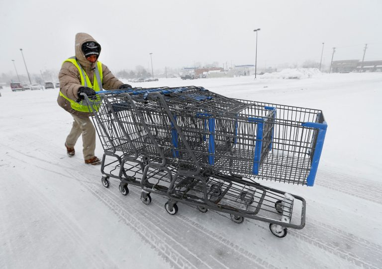 FILE - In this March 12, 2014 file photo, Anthony Avery pushes grocery carts during a snow storm in Roseville, Mich. U.S. economic growth this year will likely be at the weakest pace since the Great Recession ended, the International Monetary Fund said Wednesday, July 23, 2014, mostly because of a sharp, weather-related contraction in the first quarter. (AP Photo/Paul Sancya, File)