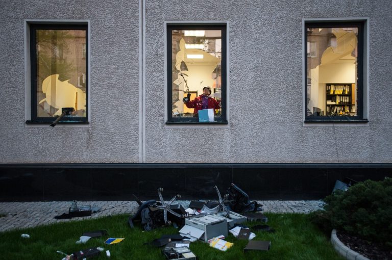 A pro-Russian activist breaks a window of the offices of Industrial Union of Donbass Corporation in Donetsk, eastern Ukraine, Saturday, May 3, 2014. (AP Photo/Evgeniy Maloletka)