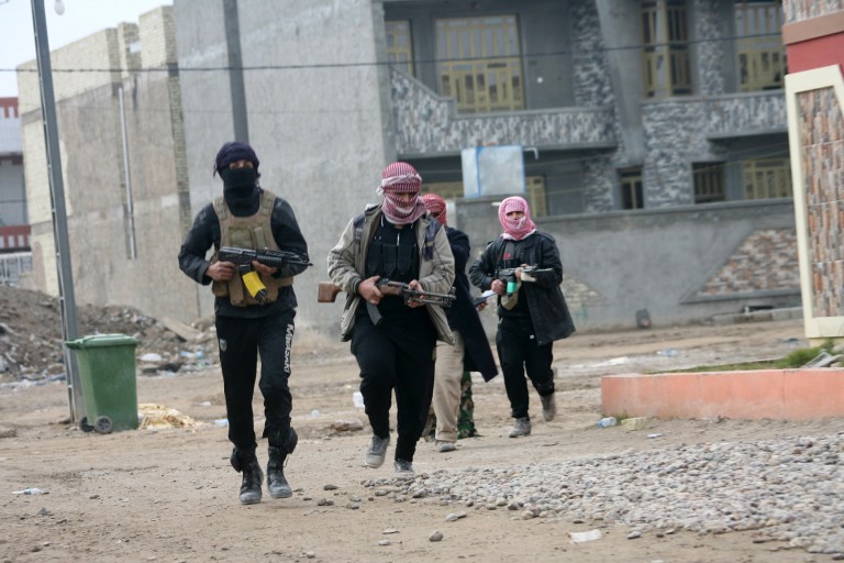 In this Sunday, Jan. 5, 2014 picture, gunmen patrol during clashes with Iraqi security forces in Fallujah, Iraq. Clashes continued late Sunday and early morning Monday between al-Qaida and Iraqi troops on the main highway that links the capital, Baghdad, to neighboring Syria and Jordan. Al-Qaida fighters and allied tribes are still controlling the center of the city where they are deployed in streets and around government buildings. (AP Photo)