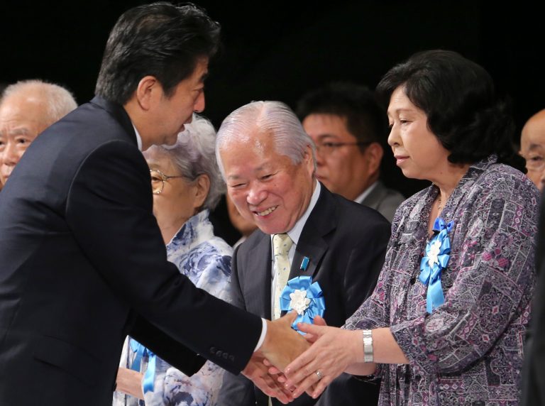 Japan's Prime Minister Shinzo Abe, left,  shakes hands with former abductee Hitomi Soga as Shigeru Yokota, center, father of Megumi Yokota who was also abducted by North Korean agents in 1977, looks on during a rally against North Korea's abductions, in Tokyo, Saturday, Sept. 13, 2014. Prime Minister Abe is turning up the pressure on North Korea to answer questions over the fate of possibly hundreds of Japanese citizens believed to have been abducted by the North's agents in the 1970s and 1980s. (AP Photo/Koji Sasahara)