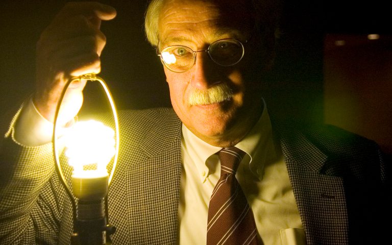 Ron Binz, Chairman of the Colorado Public Utilities Commission poses with a compact  fluorescent light bulb given to all conference goers. Binz had spoken earlier in the day on 