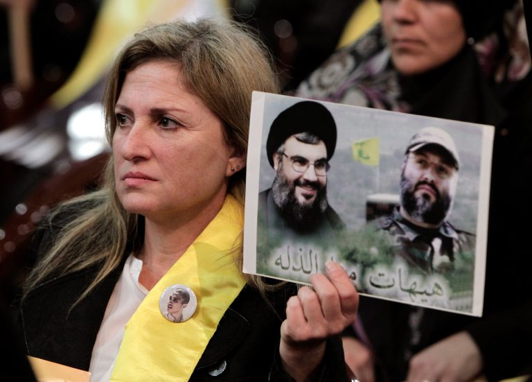 A Hezbollah supporter holds up a portrait of late Hezbollah military commander Imad Mughniyah, right, and Hezbollah leader Sheikh Hassan Nasrallah, during a ceremony marking the death of six Hezbollah fighters, including the son of Mughniyeh, and an Iranian general who were killed in an Israeli airstrike in Syria's Golan Heights last week, in the southern suburb of Beirut, Lebanon, Friday, Jan. 30, 2015. (AP Photo/Bilal Hussein)