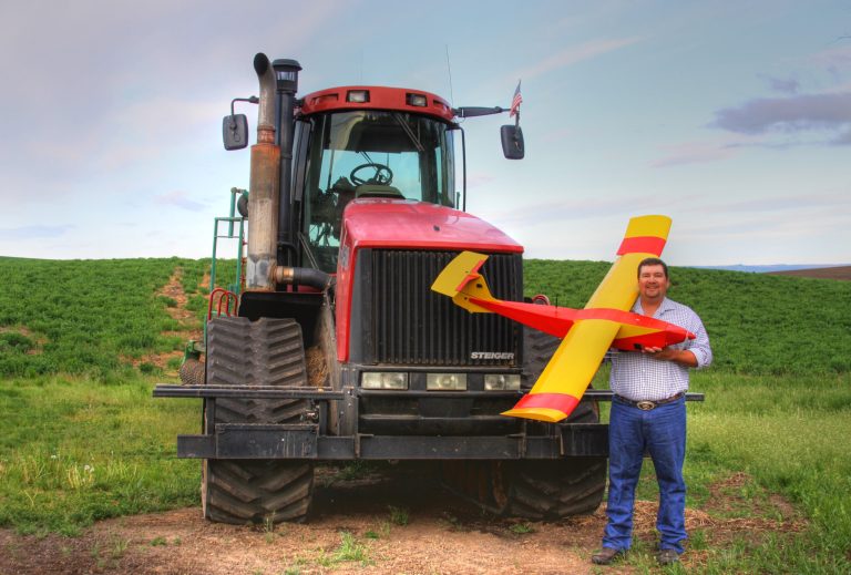 Farmer Robert Blair stands in front of his tractor holding an unmanned aircraft that he built in Kendrick, Idaho, in May 2013. Blair uses the home-made drone equipped with up to four cameras to âscoutâ his 1,500 acres of wheat, peas, barley and alfalfa and cow pasture. (AP Photo/Courtesy of Rhonda Blair)
