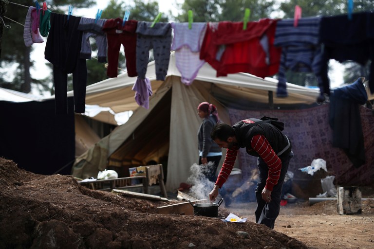 A Syrian man cooks outside his tent at Ritsona refugee camp north of Athens, on Wednesday, Oct. 19, 2016. (AP Photo/Petros Giannakouris)