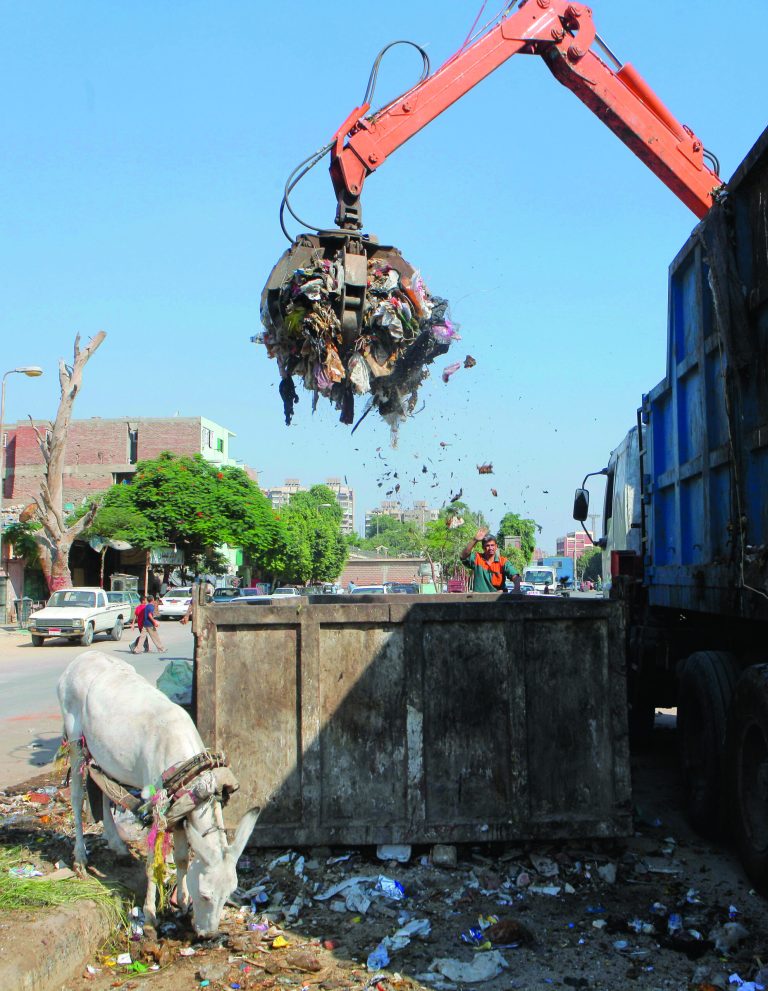 In this Thursday, Aug. 16, 2012 photo, a waste collector unloads garbage from a container in Cairo. A government modernization effort flopped. A swine flu panic prompted the mass slaughter of the pigs that recycled Cairo's organic garbage; the city's metal trash bins were easy prey for thieves, especially during the global scrap metal boom. Now the garbage crisis in the Arab world's biggest city is posing a significant test for the newly elected government that replaced longtime autocratic leaders. (AP Photo)