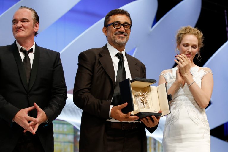 director Nuri Bilge Ceylan, center, accepts the Palm d'Or from director Quentin Tarantino and Uma Thurman during the awards ceremony for the 67th international film festival, Cannes, southern France, Saturday, May 24, 2014. (AP Photo/Alastair Grant)