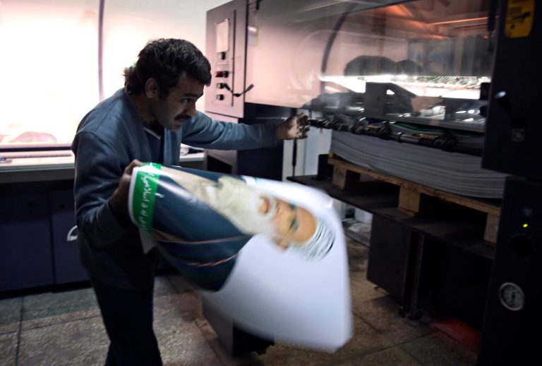 An Afghan employee holds a printed poster of a presidential election candidate at Baheer Printing Company a day before Afghanistan's presidential election campaign officially kicks off, in Kabul, Afghanistan, Saturday, Feb. 1, 2014. The posters are printed. The rallies are organized. A televised debate is planned. Campaign season for Afghanistan's presidential election kicks off Sunday, and the stakes are high for the 11 candidates vying to succeed President Hamid Karzai and oversee the final chapter in a NATO-led combat mission. (AP Photo/Massoud Hossaini)