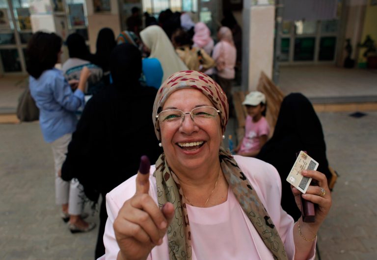   An Egyptian woman shows her ink-stained finger after voting, while others line up in front of their polling station during the first day of the presidential runoff, in Cairo, Egypt, Saturday, June 16, 2012. Egyptians voted Saturday in the country's landmark presidential runoff, choosing between Hosni Mubarak's ex-prime minister and an Islamist candidate from the Muslim Brotherhood after a race that has deeply polarized the nation. The two-day balloting will produce Egypt's first president since a popular uprising last year ousted Mubarak, who is now serving a life sentence. (AP Photo/Nasser Nasser)  