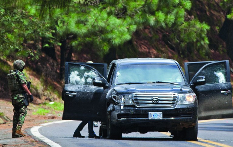 An armored U.S. Embassy vehicle is checked by military personal after it was attacked by unknown assailants on the highway leading to the city of Cuernavaca, near Tres Marias, Mexico, Friday, Aug. 24, 2012. Two U.S. government employees were shot and wounded in an attack on their vehicle south of Mexico City on Friday, a law enforcement official said. (AP Photo/Alexandre Meneghini)