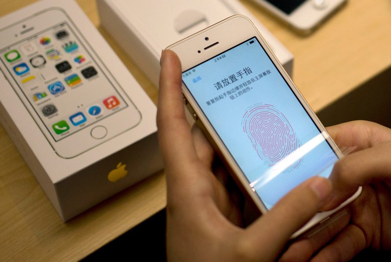 FILE - In this Sept. 20, 2013 file photo, a customer configures the fingerprint scanner technology built into the Apple iPhone 5S at an Apple store in Wangfujing shopping district in Beijing. Beyond unlocking the phone, the fingerprint can be used to authenticate the purchase of apps and content within apps. This fall, Apple will begin letting outside developers use the fingerprint ID as part of their apps. (AP Photo/Andy Wong, File)