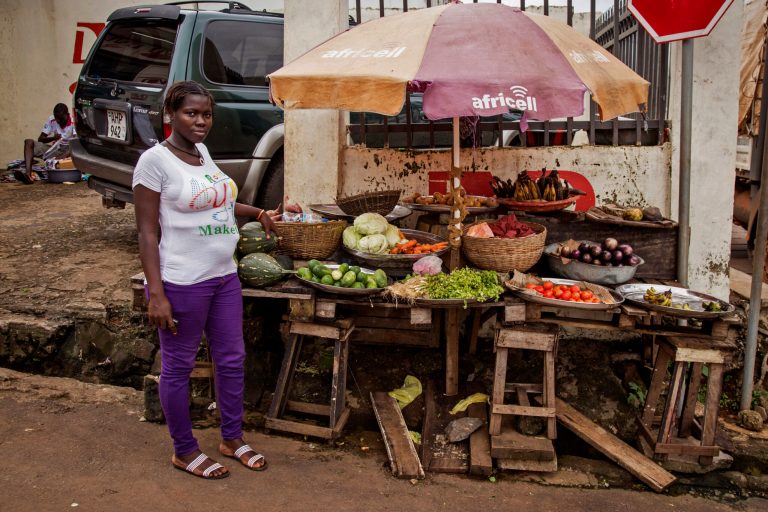 A trader poses for a photograph at her food stall in the city of Freetown, Sierra Leone, Friday, Aug. 15, 2014. The deadly Ebola virus that has killed more than 1,000 in West Africa is disrupting the flow of goods, forcing the United Nations to plan food convoys for up to a million people as hunger threatens the largely impoverished area. (AP Photo/ Michael Duff)